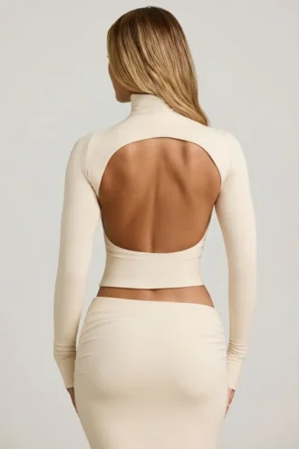 Bluză Auri din modal, cu guler înalt, fără spate și drapată, în culoarea ivoriu Bluză Auri din modal, cu guler înalt, fără spate și drapată, în culoarea ivoriu