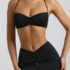 Braletă Jerika din jersey elastic cu detalii metalice și gât halter, în negru Braletă Jerika din jersey elastic cu detalii metalice și gât halter, în negru