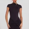 Rochie mini Blair din jersey cu guler înalt, cu volane și spate decupat, în culoarea neagră Rochie mini Blair din jersey cu guler înalt, cu volane și spate decupat, în culoarea neagră